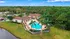 Aerial view of a luxurious apartment complex with a sparkling swimming pool surrounded by palm trees and lush greenery, offering a serene and tropical living experience.