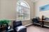 Bright home office with an arched window, elegant desk setup, and comfortable seating, perfect for productivity and inspiration.