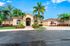 Elegantly designed apartment exterior with tropical landscaping and palm trees under a bright blue sky.