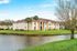 Charming apartment building with picturesque water views, surrounded by lush greenery and palm trees, under a clear blue sky.
