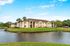 Charming apartment complex with serene lakeside view, lush greenery, and palm trees, offering a peaceful living environment.