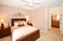 Inviting bedroom with elegant decor, featuring a plush bed, stylish lamps, and a view into a luxurious en-suite bathroom.