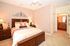 Warm and inviting bedroom with plush bedding, elegant wooden furniture, and en-suite access to a stylish bathroom.