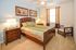 Cozy bedroom with elegant wooden furniture, inviting queen bed, and bright natural lighting.