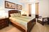 Inviting bedroom with a cozy bed adorned with pastel linens, wooden furnishings, and elegant decor for a relaxing retreat.