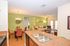 Chic open-concept living and dining area with vibrant green accent wall, warm lighting, and stylish decor, featuring a comfortable seating arrangement and modern kitchen island.