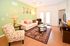 Inviting living room with a modern design, featuring a vibrant accent wall, comfortable seating, and a chic glass coffee table on stylish patterned flooring.