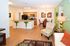 Inviting open-plan kitchen and living area with modern decor, featuring vibrant green bar stools, wooden cabinetry, and stylish dining space.