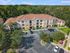 Charming apartment complex nestled in lush greenery, featuring a warm-toned exterior and well-maintained surroundings with ample parking space.