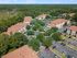 Charming residential community with terracotta-roofed apartment buildings surrounded by lush greenery, offering ample parking and a serene suburban atmosphere.