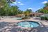 Inviting outdoor retreat featuring a sparkling circular hot tub and a luxurious resort-style pool surrounded by lush greenery and comfortable lounge chairs.