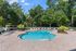 Inviting and serene outdoor swimming pool surrounded by lush greenery and cozy lounge chairs, perfect for relaxation and enjoyment.