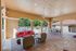 Elegant outdoor covered patio with vibrant seating and dining area, overlooking a luxurious pool and lush greenery.