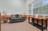Bright and inviting living room with modern gray couch, decorative pillows, elegant lamps, in a cozy carpeted setting with large windows for abundant natural light.