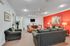 Vibrant living room with a striking red accent wall, modern decor, plush seating, and a stylish layout, ideal for relaxation and entertaining.
