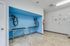 Modern pet grooming station with blue accent walls, featuring professional drying equipment and artistic animal portraits.