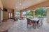 Elegant outdoor patio with stylish wicker furniture, ceiling fans, and a scenic view of greenery and a pool, perfect for relaxation and entertaining.