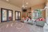 Charming outdoor patio with cozy wicker furniture, red cushions, elegant ceiling fan, and stylish French doors.