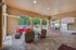 Inviting outdoor patio space with elegant archways, stylish wicker furniture with red cushions, and a dining area overlooking a serene pool and lush greenery.