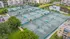 Vibrant aerial view of a community featuring multiple tennis courts with green canopies, surrounded by lush greenery and modern apartment buildings.