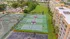 Aerial view of vibrant apartment complex with lush greenery, tennis courts, and spacious outdoor areas.