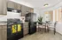 Bright, modern kitchen with sleek black appliances, wood cabinetry, and a cozy dining nook by a large window.