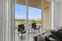 Inviting balcony view from a chic apartment with cozy seating, overlooking serene waters and lush green landscape.