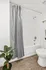 Elegant bathroom with a sleek bathtub, modern gray shower curtain, and stylish wooden flooring, enhanced by a decorative plant for a spa-like ambiance.