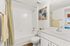 Bright modern bathroom featuring stylish fixtures, a full bathtub, elegant wall art, and a large mirror for a refreshing ambiance.