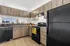 Modern kitchen with sleek black appliances, elegant wooden cabinetry, and stylish backsplash.