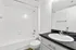Bright and modern bathroom with sleek fixtures, featuring a pristine white bathtub and contemporary vanity sink.