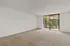 Bright and airy living room with plush carpet and large sliding glass doors overlooking lush greenery.