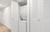 Convenient in-unit laundry with stacked washer and dryer, neatly tucked behind modern white shutters.