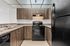 Modern kitchen with sleek dark wooden cabinets, stainless steel double sink, and a stylish black appliance suite.