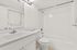 Bright and modern bathroom with elegant fixtures, spacious vanity, and pristine white tiles creating a serene ambiance.