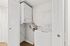 Compact laundry area with a modern washer and dryer neatly stacked for convenience, featuring sleek white cabinetry and wooden flooring.