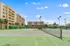 Spacious apartment complex with inviting tennis courts under a clear blue sky, surrounded by lush greenery.
