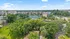 Scenic aerial view of a lush residential complex with modern apartment buildings, surrounded by vibrant greenery and tennis courts.