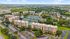 Aerial view of a vibrant apartment complex featuring lush greenery, spacious parking, and extensive tennis courts, ideal for active lifestyles and community living.