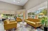 Bright and inviting lounge area featuring modern yellow sofas, a stylish geometric rug, and large windows with lush garden views.