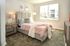 Elegant bedroom with plush carpet, chic pink bedding, and abundant natural light from large windows.
