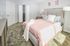 Inviting bedroom with plush carpeting, modern decor, and a cozy bed framed by soft pink linens and accent pillows, enhanced by soft natural lighting.