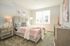 Bright and inviting bedroom with a plush bed, elegant decor, and natural light streaming through a large window.