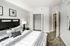 Elegant bedroom featuring stylish decor, cozy bed with patterned linens, and a spacious closet in a modern apartment.