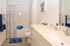 Bright and cheerful bathroom featuring a sleek sink, inviting bathtub with playful polka dot shower curtain, and charming decor with potted succulents.