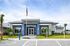 Modern and sleek building facade featuring blue accents, lush greenery, and accessible parking, creating an inviting atmosphere.