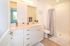 Bright and modern bathroom featuring sleek white cabinetry, elegant fixtures, and a spacious shower area with soft lighting, offering a refreshing and serene atmosphere.