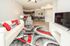 Contemporary open-plan living room with sleek gray and red accents, featuring plush seating, a modern dining area, and a stylish kitchen bar.