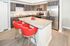 Contemporary kitchen with sleek granite countertops, stainless steel appliances, and vibrant red bar stools.