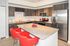 Modern kitchen with granite countertops, stainless steel appliances, and vibrant red barstools, creating an inviting space for culinary adventures.